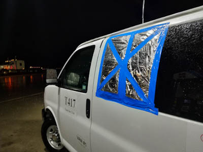 The window of a white support van is covered with a silver space blanket and blue duct tape after being blown out in a hailstorm on the Colorado-Kansas border.